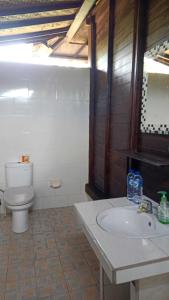La salle de bains est pourvue d'un lavabo blanc et de toilettes. dans l'établissement Perdana Homestay Lembongan, à Nusa Lembongan