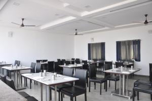 une salle à manger avec des tables blanches et des chaises noires dans l'établissement Hotel SSLR ,Gangavathi, à Hampi