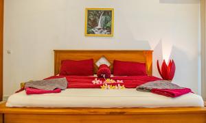 a large red bed with red pillows and flowers on it at Senggigi Homes & Apartments in Senggigi 