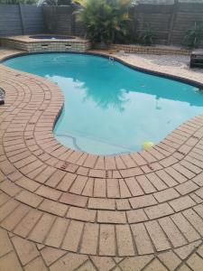 a swimming pool with a brick pattern around it at Puleng's Granny Flat in Richards Bay