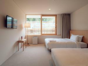 a hotel room with two beds and a window at Hatago Vison 