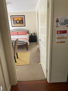 1 dormitorio con 1 cama y puerta que conduce a un pasillo en Private room with ensuite and parking close to Wollongong CBD en Wollongong