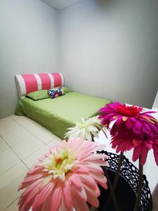 two pink and white flowers in a basket next to a bed at BR Guesthouse Kuantan in Kuantan