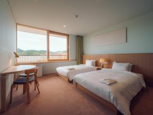 a hotel room with two beds and a desk and a window at Hatago Vison 