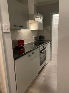 a kitchen with white cabinets and black counter tops at The Vault – cosy apartment in central Hove / Brighton in Brighton & Hove