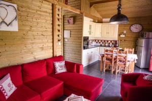 a living room with a red couch and a kitchen at Le Domaine des Fagnes in Sains-du-Nord