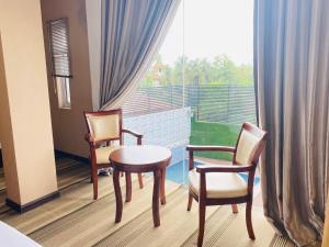 een kamer met 2 stoelen, een tafel en een raam bij Sundale Hotel in Divulapitiya