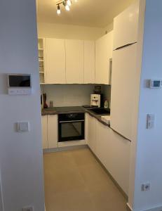 a small kitchen with white cabinets and appliances at Apartman ARIA in Zagreb