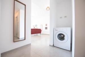 a washing machine in a white room with a mirror at PORT CITY HAIFA - Bat Galim 20m from the beach in Haifa