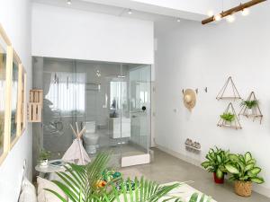 baño blanco con ducha de cristal y plantas en 闆娘公寓 en Kaohsiung