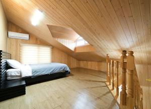 a attic bedroom with a bed and a staircase at Ddeulae Pension in Suncheon
