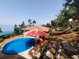 a swimming pool with an umbrella and a hammock at Robinson Sunset Guest House in Ohrid