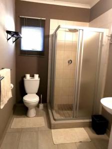 a bathroom with a shower and a toilet and a sink at Unit Blessed in Oudtshoorn
