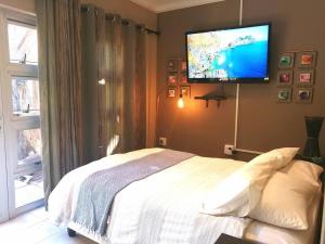 a bedroom with a bed with a flat screen tv on the wall at Unit Blessed in Oudtshoorn