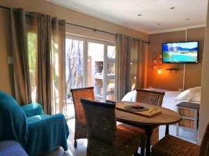 a room with a table and a bed and a television at Unit Blessed in Oudtshoorn