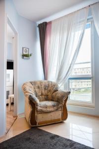 an old chair in a living room with a window at Wola Pleasure Place Apartment in Warsaw