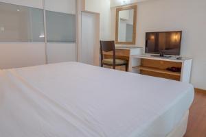 a bedroom with a white bed and a television at The CEO Executive Suites in Bayan Lepas