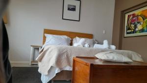 a bedroom with a bed with white sheets and pillows at Limbila House in Cape Town