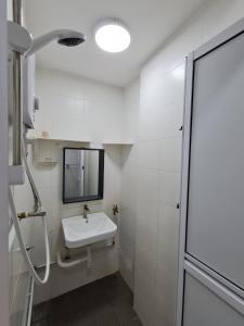 Un baño blanco con lavabo y espejo. en Homestay near to Georgetown, en Jelutong