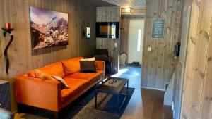 uma sala de estar com um sofá laranja e uma mesa em Flott leilighet i Vestlia - ski in/ski out em Geilo