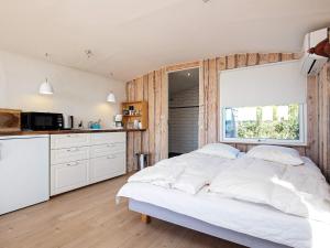 Cet appartement comprend une chambre avec un grand lit blanc et une cuisine. dans l'établissement Holiday home Bogense II, à Bogense