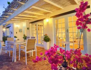 a patio with a table and chairs and flowers at Hout Bay Beach Cottage in Hout Bay
