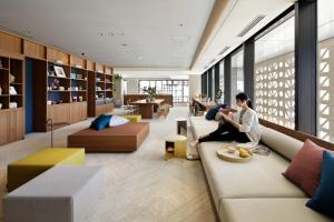 a couple sitting on a couch in a living room at OMO5 Okinawa Naha by Hoshino Resorts in Naha