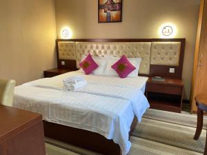 a hotel room with a large bed with pink pillows at Sundale Hotel in Divulapitiya