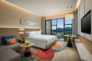 a hotel room with a bed and a couch and a tv at Holiday Inn Resort Guiyang Qingyan, an IHG Hotel in Guiyang