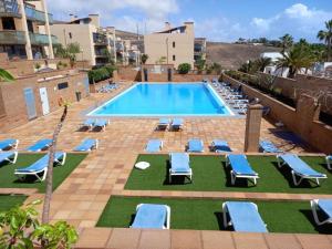 - une piscine avec des chaises longues bleues dans l'établissement Apartamento del Mar, à Playa Jandía