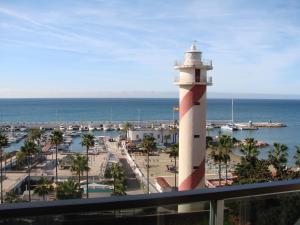 a lighthouse in a marina next to the ocean at Apto Puerto Deportivo el Faro Marbella in Marbella