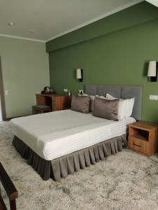 een groot bed in een kamer met een groene muur bij Le Grande Plaza Hotel in Tasjkent