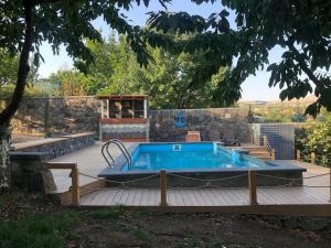 a pool on a wooden deck next to a house at Cheerful 3-bedroom villa with pool in Oganavan