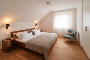 ein Schlafzimmer mit einem Bett, einem Stuhl und einem Fenster in der Unterkunft Haus4Zimmer - Luxus mit Blick über den Bodensee - mit Garage in Bregenz