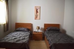 Un dormitorio con dos camas y una mesa con lámpara. en Da Vinci 3 bedroom Apartment, en Mellieħa