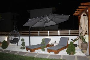 eine Terrasse mit 2 Stühlen und einem Sonnenschirm in der Unterkunft Azure Bliss Suites in Nikiti