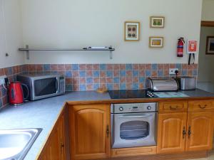 a kitchen with a stove and a microwave at Bo Nan Taigh Cottage in Aberfoyle