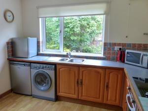 a kitchen with a sink and a washing machine at Bo Nan Taigh Cottage in Aberfoyle