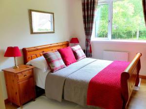 a bedroom with a bed with pink pillows and a window at Bo Nan Taigh Cottage in Aberfoyle