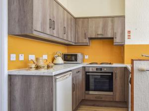 una cocina con armarios de madera y una pared amarilla en Whitby Apartment, en Commondale