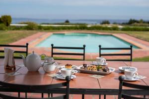 a table with a plate of food next to a pool at Greenhill Farm Manor House Plettenberg Bay - Private House Sleeps 8 in Plettenberg Bay