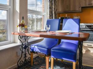 a kitchen with a wooden table and blue chairs at Grosmont Apartment in Commondale