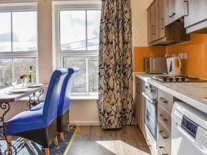 a kitchen with a blue chair and a table and window at Grosmont Apartment in Commondale