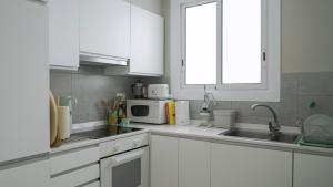 a white kitchen with white cabinets and a microwave at At home, in the Heart of Sitges in Sitges