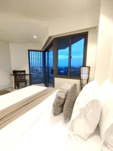 a bedroom with a large bed with white sheets and pillows at ReLuxe マリン Condo in Maribago