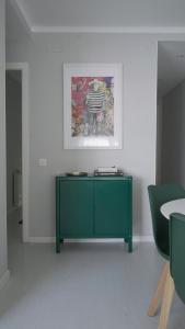 a green cabinet in a room with a painting at At home, in the Heart of Sitges in Sitges