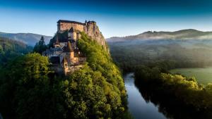 a castle on top of a hill next to a river at Chata na Orave so saunou a kúpacou kaďou in Námestovo