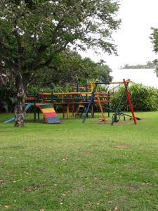 a park with colorful playground equipment and a tree at CARIBBEAN POOL-SIDE VILLA 1148 in Port Edward