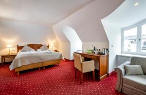 a bedroom with a bed and a desk and a chair at Hotel am Mirabellplatz in Salzburg