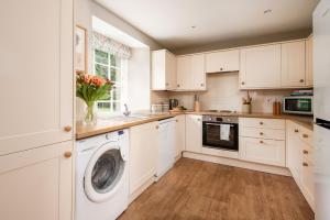 a kitchen with white cabinets and a washer and dryer at Crailing Cottage in Jedburgh